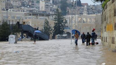 People cross a flooded street in Amman. Reuters