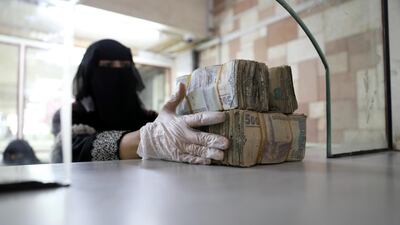 An employee takes bundles of Yemeni Riyal at the Central Bank of Yemen in Sanaa. REUTERS