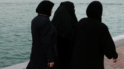 Women walk along the Abu Dhabi Breakwater with a skyline shrouded in fog as rain and wind swept parts of the country on Tuesday. Christopher Pike / The National