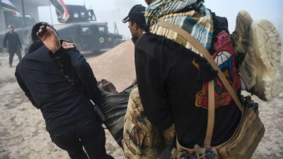 Iraqi Counter Terrorism Section (CTS) members carry an injured comrade during clashes with Islamic State (IS) group jihadists near the village of Bazwaya, on the eastern edges of Mosul. Bulent Kilic / AFP