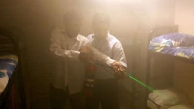 Trainees take aim and guide the green laser beam of a fire extinguisher at the source of a potential fire as part of a series of safety exercises.