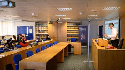 Lecturer Ian Bowden teaches law students from behind a perspex screen at the University of Bolton. Oli Scarff / AFP
