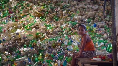 A girls sits next to a pile of used plastic bottles in a recycling factory in Dhaka, Bangladesh, on May 5. AFP