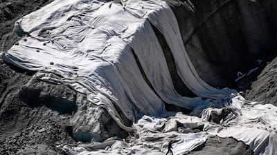 A man walks near big sheets used to slow down the melting above the grotto carved inside the Mer de Glace glacier in Chamonix. AFP