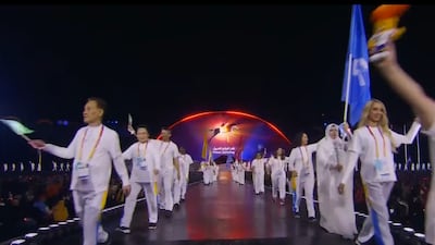 A parade of flag-waving athletes takes to the stage as the names of the participating sports are announced. Screen grab / YouTube