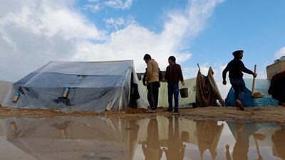 Palestinians who fled their homes amid Israeli bombardment attempt to remove water from near their tents. Reuters