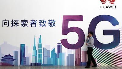 A man talks on his mobile phone beside Huawei's billboard featuring 5G technology at the PT Expo in Beijing, China.