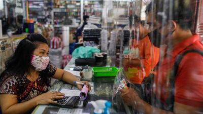 A vendor tends to a customer behind a makeshift barrier on the first day of the Philippine capital's gradual reopening since the lockdown. Reuters