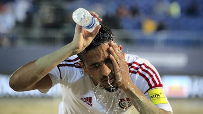 A UAE's player gets sand out of his face during the game.