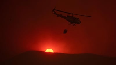 A helicopter carries water as the sun sets in the background while fighting the Mendocino Complex fire in Lakeport, California. Josh Edelson/AFP