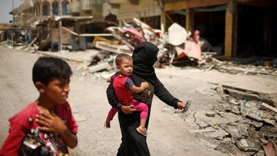 An Iraqi family walks past destroyed shops, in western Mosul, Iraq July 31, 2017. REUTERS/Suhaib Salem
