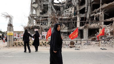 Iranians walk past portraits of victims killed in a US-Israeli air strike in Tehran. AFP