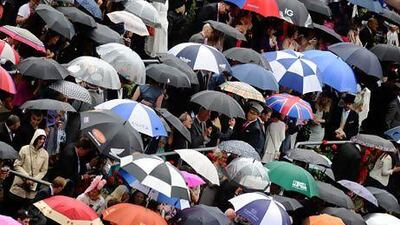 Racegoers shelter from the rain at Royal Ascot. The UK's poor weather is encouraging demand for foreign holidays. Alan Crowhurst / Getty Images