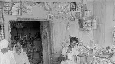 A cheerful trader shows off his wares in the Abu Dhabi souq in 1962. They include Heinz beans, tinned peaches, and, of course, Vimto. Courtesy: Guy Gravett