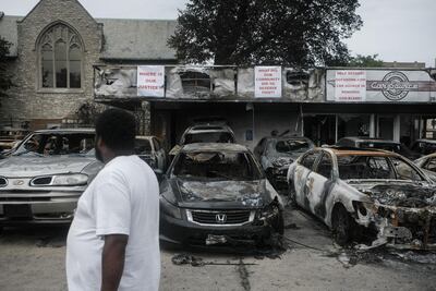 A resident inspects burned out cars at a used car dealership in Kenosha. Bloomberg