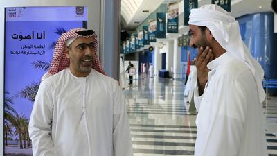 Candidate Mohammed Al Mansouri, left, greets a voter arriving at Abu Dhabi National Exhibition Centre to cast his ballot on the last day of early voting for the FNC elections, which gave candidates a chance to win over some last-minute support. Ravindranath K / The National