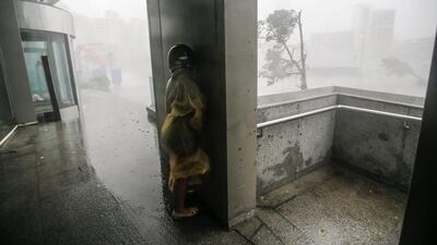 A motorist takes cover on a wall as winds and rain from super typhoon Meranti in southern Taiwan. EPA