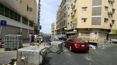 Cars pass garbage containers thrown onto the road to prevent riot police from entering the street in the centre of Manama yesterday.