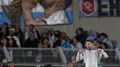 Lionel Messi on the pitch in front of a banner of him kissing the World Cup trophy at the Monumental stadium in Buenos Aires. AFP