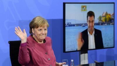 German Chancellor Angela Merkel and Bavaria's State Premier and leader of Bavaria's conservative Christian Social Union (CSU) party Markus Soeder, seen on screen via video call, wave to journalists at the end of a press conference following talks with Germany's state premiers on the current situation of the country's coronavirus vaccination campaign, at the Chancellery in Berlin. AFP