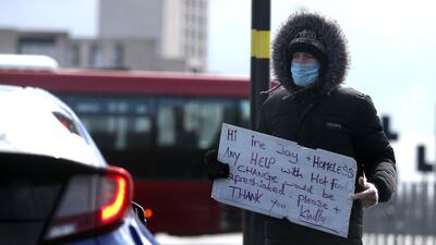 A homeless man wearing a protective face mask appeals for help to passing motorists in Birmingham. Reuters