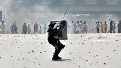 Demonstrators throw stones at a policeman during clashes in Islamabad on Friday.