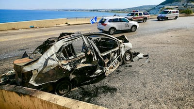 A UN peacekeeping force vehicle drives past the wreckage of a car that was targeted in Israeli strike early on Saturday near the southern Lebanese town of Naqoura. AFP