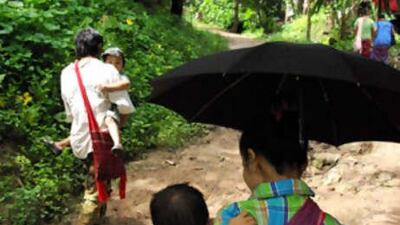 Karen families walk to church. Despite living in a refugee camp in Thailand, members of this Myanmar hill tribe are reluctant to leave the camp and move away from their homeland, which has made resettlement programs hard.