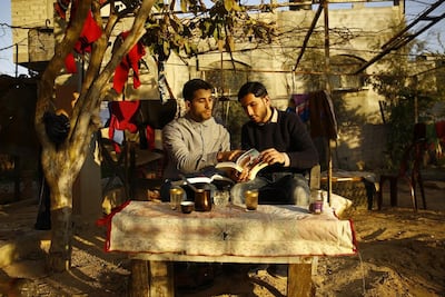 Mosab Abu Toha (left) looks at books with his friend Shafi Salem in the garden of Mosab's family home in Beit Lahia, northern Gaza, on February 20, 2017. AFP Photo