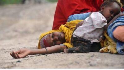 A mother lies with her child on a road in Mogadishu while waiting for assistance at a makeshift medical camp.