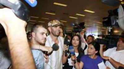 A crew member of the Mavi Marmara, wearing cap at centre, is surrounded by media upon his arrival in Istanbul.