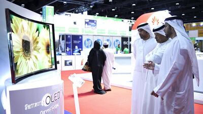 Visitors look at Samsung’s curved television on display at the Abu Dhabi Electronics Shopper. Lee Hoagland / The National