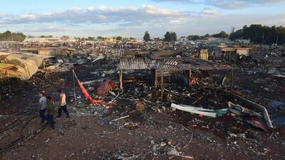 Forensic investigators pour over the charred remains of the fireworks market. Ronaldo Schemidt / AFP Photo