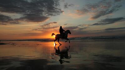 A Palestinian man rides a horse on a beach during the last sunset of 2019, in Gaza City. Reuters