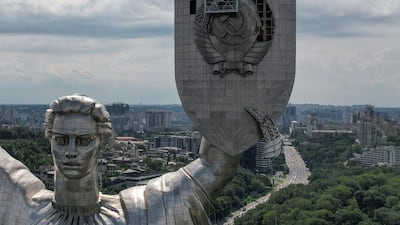 Workers remove a Soviet emblem from the Motherland monument in Kyiv. Reuters