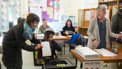A woman helps her daughter to cast a vote at a polling station during general elections in Dublin, Ireland. EPA
