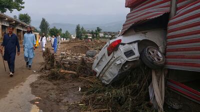 People walk past shops damaged after flash flooding on the outskirts of Pir Baba, in Pakistan's northwest. AP