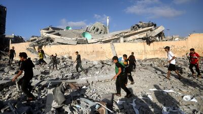 Palestinians walk by a destroyed mosque following an Israeli air strike in Khan Younis. AP