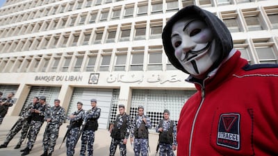 A demonstrator looks on as Lebanese policemen stand guard outsidet the Central Bank in Beirut, December 16, 2018. AFP