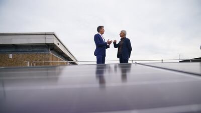 Mr Khan and shadow energy secretary Ed Miliband stand behind solar panels on the roof of Stoke Newington School in north London, during a visit to announce a new climate action plan for the city. PA