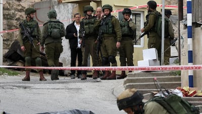 Israeli soldiers gather at the body of a Palestinian man who was killed in Hebron on Thursday. Hazem Bader / AFP