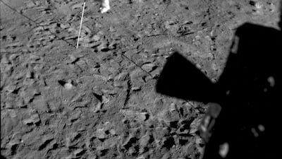 A US flag planted at Tranquility Base on the surface of the moon, and a silhouette of a thruster at right, seen from a window in the Lunar Module. AP