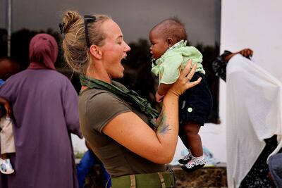 A British military medic entertaining a baby at Wadi Seidna air base near Khartoum before boarding an RAF aircraft bound for Cyprus. PA