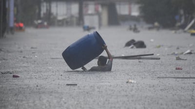 A man carries a plastic water butt through a flooded street in Manila amid heavy rains brought by Typhoon Gaemi. AFP