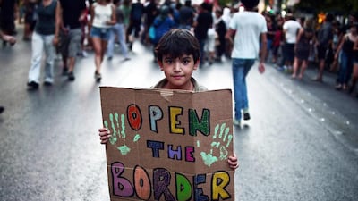 A child holds a placard reading 'Open the border' during a demonstration in support to refugees and migrants in front of Athens municipality building. Thousands of refugees and their supporters marched towards the Athens municipality building and the the offices of the ruling Syriza party, after an attack last week on the housing squat for refugees and migrants. Protesters demanded better protection for the refugees and migrants. AFP