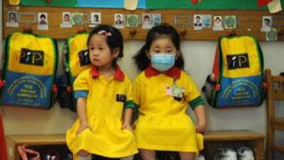 A masked girl sits with a classmate at a kindergarten in Hong Kong on June 11 2009.