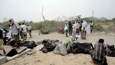 Men stand near bodies of victims of the explosion at a bullet factory in the southern Yemeni town of Jaar.