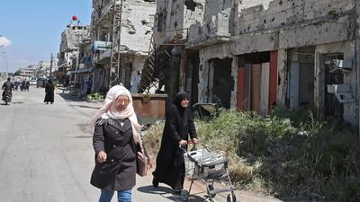 Syrians walk past buildings heavily damaged during Syria's civil war, in the central city of Homs. AFP