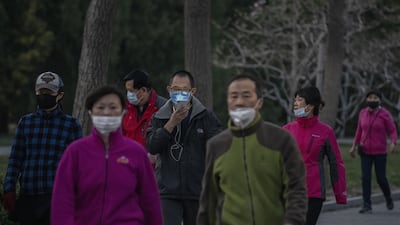 People wear protective masks as they walk at Ritan Park in Beijing, China. Getty Images