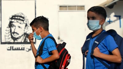 Palestinian students, wearing protective face masks, gather in the courtyard, next to a graffiti of late leader Yasser Arafat, on the first day of school in the village of Salem east of Nablus in the occupied West Bank on September 6, 2020, during the coronavirus pandemic. AFP